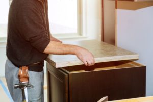 A kitchen contractor places a laminate top onto a cabinet. Formica has been a staple in kitchen design for generations. There are many reasons to choose laminate countertops.